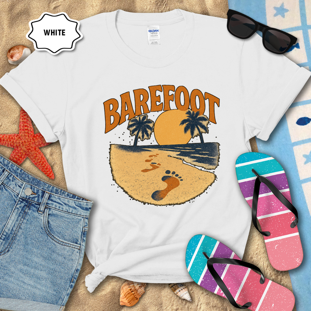 White t-shirt with 'Barefoot' graphic design on a beach-themed background with sunglasses, flip-flops, and denim shorts.