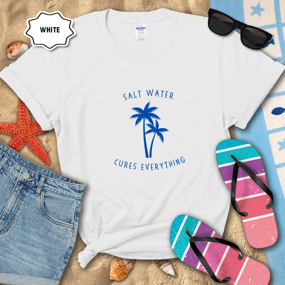 White t-shirt with 'Salt Water Cures Everything' design on a sandy background with flip-flops and sunglasses.