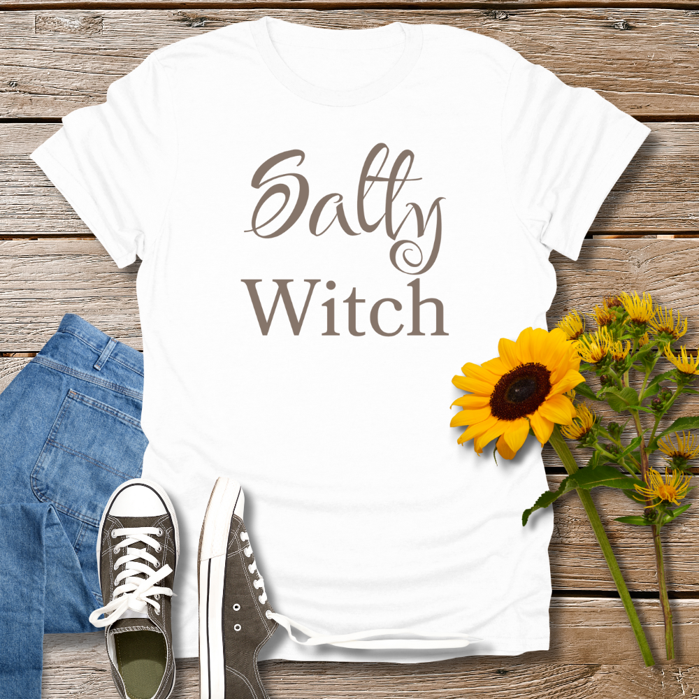White t-shirt with 'Salty Witch' text, blue jeans, brown shoes, and sunflowers on a wooden surface