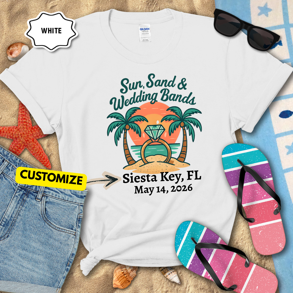 White t-shirt with tropical design and customizable text, surrounded by beach accessories.