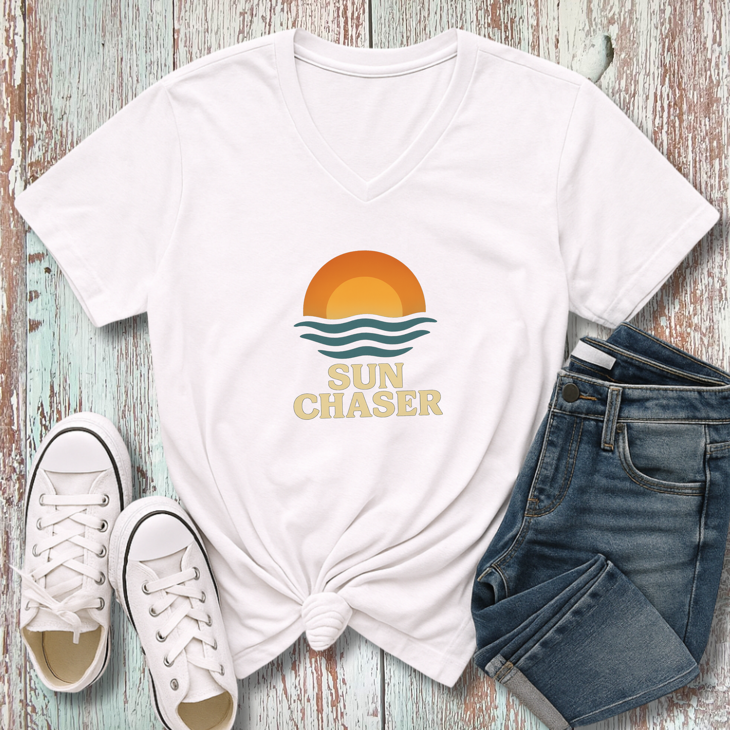 White t-shirt with 'Sun Chaser' design, white sneakers, and blue jeans on a wooden surface