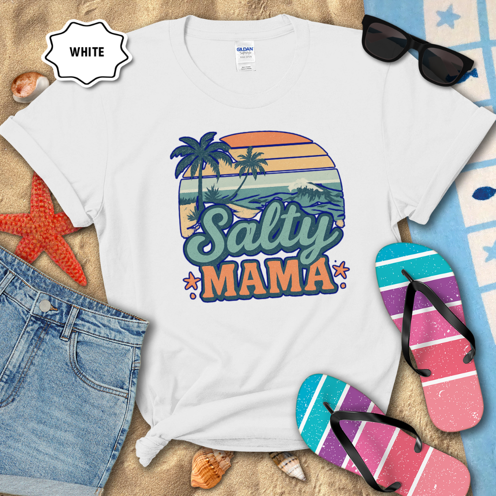 White t-shirt with 'Salty Mama' design on a sandy background with flip-flops and sunglasses.