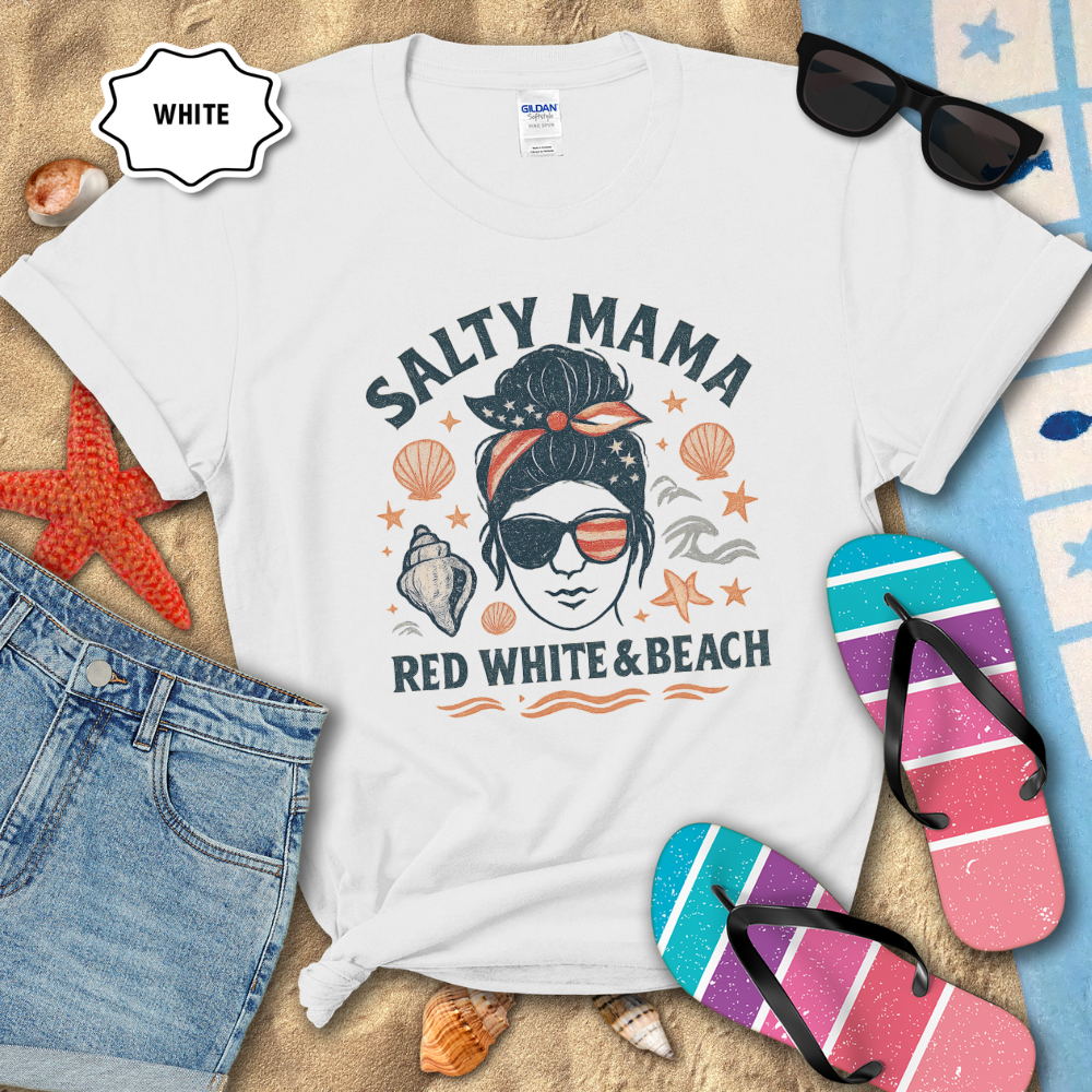 White t-shirt with 'Salty Mama Red White & Beach' design on sand with sunglasses, flip-flops, and denim shorts.