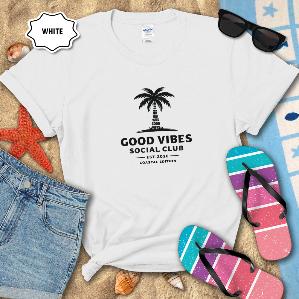 White t-shirt with 'Good Vibes Social Club' design on a beach setting with sunglasses, flip-flops, and denim shorts.